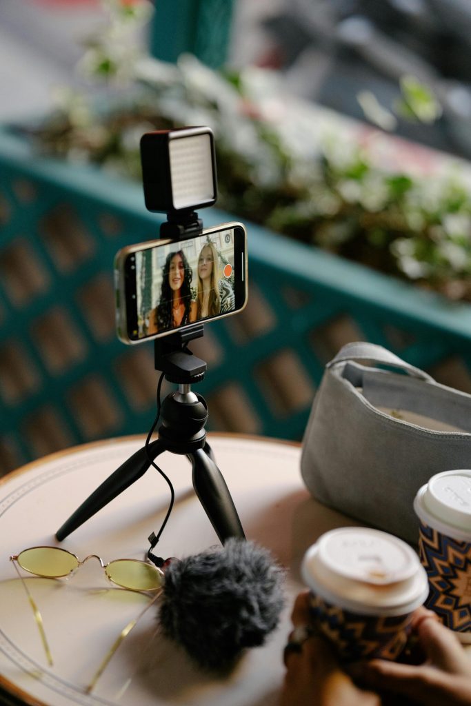 Young Girls Recording Themselves with a Smartphone on a Tripod in a Cafe